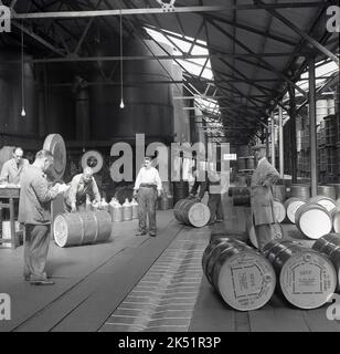 1950s, historiques, ouvriers dans une zone d'un dépôt industriel déplaçant de grands barils d'acier d'huiles moteur à vide, Wandsworth, Londres, Angleterre, Royaume-Uni. Les barils de métal précieux avaient un dépôt de 40/- shillings chacun et a dû être retourné vide au dépôt Wandsworth après utilisation. L'American Vacuum Oil Co a été créée en 1866 et sa marque déposée 'Mogiloil' a été utilisée pour la première fois par Vacuum Oil en Grande-Bretagne. Banque D'Images