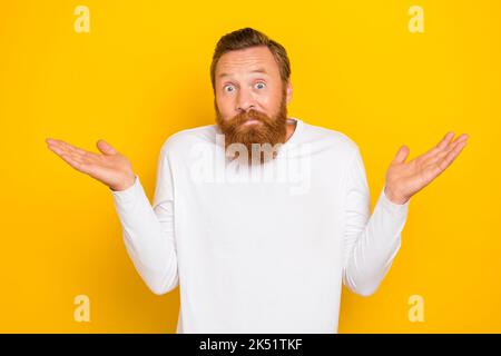 Photo portrait d'un jeune homme attrayant haussant les épaules trouplée ne savez pas porter des vêtements blancs élégants isolés sur fond jaune Banque D'Images