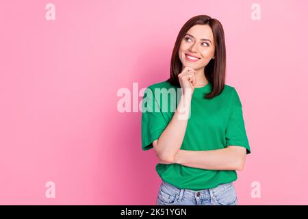 Photo portrait de la jeune femme magnifique esprit look vide espace sourire toucher menton porter élégant vêtement vert isolé sur fond rose Banque D'Images