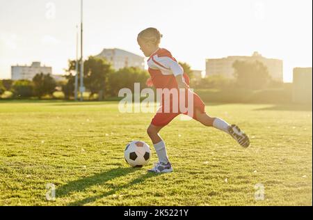 Football, football et entraînement de fille de sport sur le terrain se préparant pour le match, le jeu ou la compétition sur terrain de pelouse en plein air. Santé, fitness et kick-ball pour enfants Banque D'Images