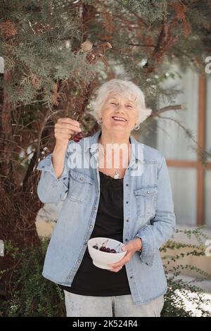 Femme âgée tenant un bol de cerises mûres Banque D'Images