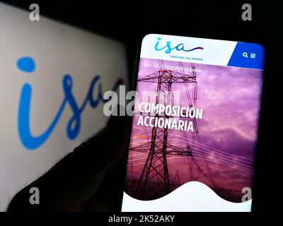 Personne tenant un téléphone mobile avec la page web de la société colombienne Grupo ISA sur l'écran devant le logo d'affaires. Concentrez-vous sur le centre de l'écran du téléphone. Banque D'Images