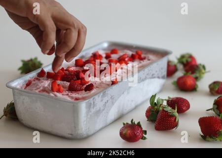 Crème glacée à la fraise maison, prise au congélateur dans un moule à pain servi avec des tranches de fraise sur le dessus. Crème glacée à trois ingrédients à base de crème fraîche Banque D'Images