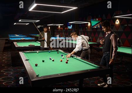 Amis jouant au billard dans la salle de billard Banque D'Images