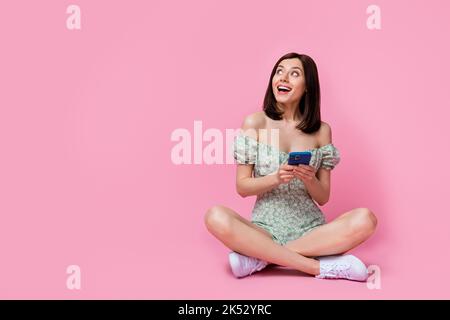 Photo pleine grandeur de douce dame s'asseoir téléphone chercher port bottes isolées sur fond de couleur rose Banque D'Images