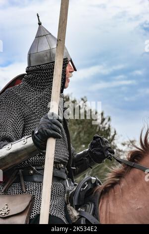 Ancien cavalier en armure de courrier en chaîne, casque avec arme de brochet en bois équipé sur le ciel bleu cheval Banque D'Images