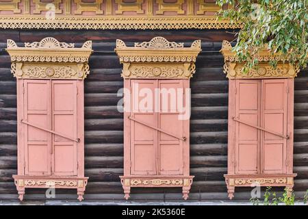 Anciennes fenêtres en bois peintes. Architecture jaune sculptée, volets de corail fermés. Ulan-Ude, Russie. Banque D'Images