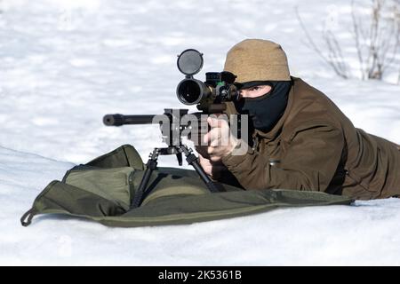 Un fusil de sniper avec une vue optique dans les mains homme visant à poser sur la neige ensoleillé jour d'hiver Banque D'Images