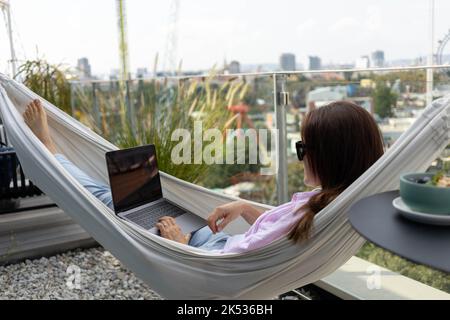 jeune femme indépendante travaillant dans un hamac sur la terrasse Banque D'Images