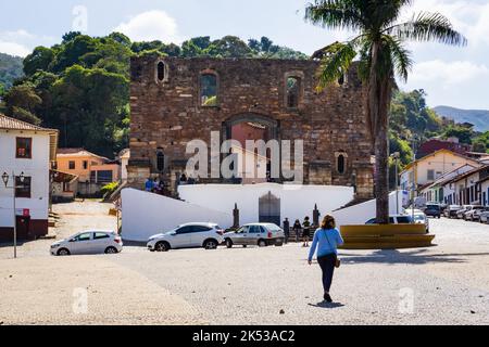 Femme marchant à Praça Delfim Moreira en face de Igreja de Nossa Senhora do Rosário dos Pretos da Barra à Sabará, Minas Gerais, Brésil. Banque D'Images