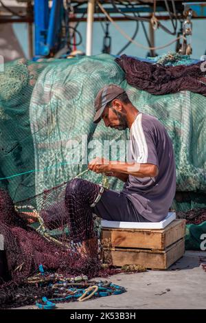 pêcheur grec réparant des filets chalutiers sur le quai ou sur le port dans la ville de zante, zakynthos, grèce. Banque D'Images