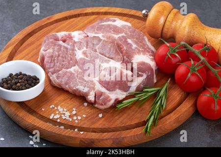 Viande crue avec tomates sur une surface noire Banque D'Images