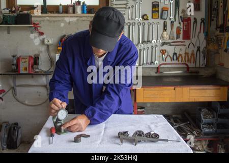 Photo d'un mécanicien dans son atelier prenant des mesures avec une jauge d'épaisseur et un micromètre. Exercice pratique et mécanique de précision. Banque D'Images