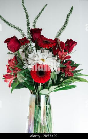 La vue verticale d'un bouquet de fleurs rouges et blanches dans le vase isolé sur fond blanc Banque D'Images