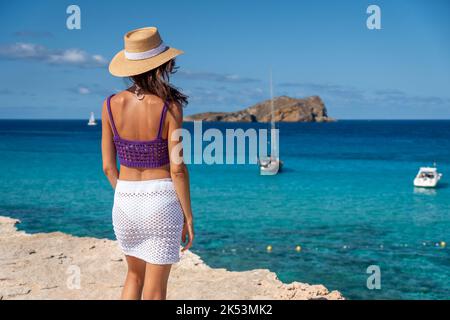 Femme Brunette avec chapeau, jupe blanche et haut violet sur les rives de la Méditerranée Banque D'Images