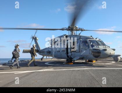 EAUX À L'EST DE LA PÉNINSULE CORÉENNE (SEPT 30, 2022) le lieutenant Taehyung Kim, à gauche, marin de la marine de la République de Corée, entre dans un hélicoptère MH-60s Sea Hawk affecté aux « Golden Falcons » de HSC-12 à bord du destroyer à missiles guidés de classe Arleigh Burke USS Benfold (DDG 65), septembre 30. Benfold, et Carrier Strike Group (CSG) 5, mène un exercice de guerre trilatéral contre les sous-marins avec la JMSDF et la ROK Navy. Les opérations entre le groupe Reagan Strike, JS Asahi, et ROKS Munmu the Great, ont impliqué l'exploitation avec un sous-marin américain pour améliorer l'interopérabilité entre les nations à l'appui d'un libre et Op Banque D'Images