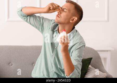 Jeune homme avec des saignements de nez et des tissus à la maison Banque D'Images