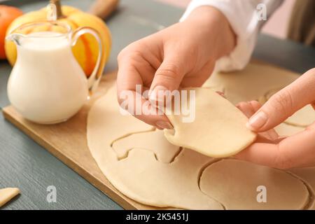 Femme avec un morceau de pâte crue pour Halloween cookie sur fond de bois foncé, gros plan Banque D'Images