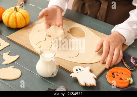 Femme faisant des biscuits d'Halloween à table en bois sombre, gros plan Banque D'Images