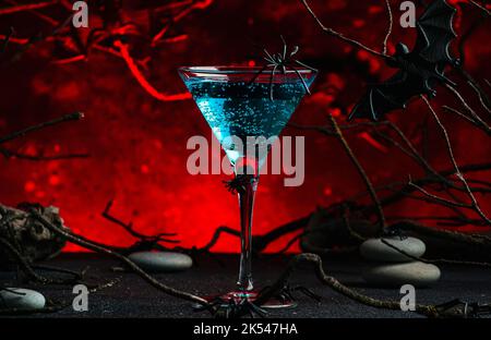 Halloween sorcière potion cocktail alcoolique sur fond rouge foncé effrayant avec branches tordues, chauves-souris, pierres et araignées, boisson de fête pour la fête Banque D'Images