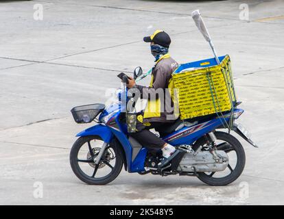 SAMUT PRAKAN, THAÏLANDE, OCT 04 2022, Un livrant conduit une moto avec le téléphone mobile dans sa main Banque D'Images