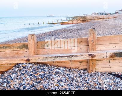 Worthing Beach brise-lames en bois menant à la mer au-dessus de la plage de pierres au lever du soleil Royaume-Uni. Banque D'Images