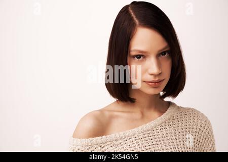 Calme et calme. Jeune femme aux cheveux sombres sur fond blanc. Banque D'Images