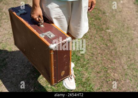 Fille tenant une vieille valise en cuir dans ses mains Banque D'Images