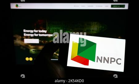 Personne tenant un smartphone avec le logo de la compagnie pétrolière nationale nigériane limitée (NNPC) à l'écran devant le site Web. Mise au point sur l'affichage du téléphone. Banque D'Images