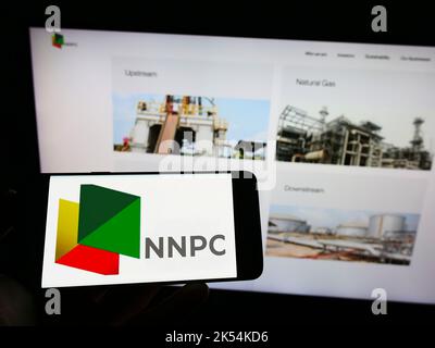 Personne tenant un téléphone portable avec le logo de la compagnie pétrolière nationale nigériane limitée (NNPC) à l'écran devant la page Web. Mise au point sur l'affichage du téléphone. Banque D'Images