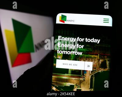 Personne tenant un téléphone portable avec le site Web de la compagnie nationale de pétrole nigériane limitée (NNPC) à l'écran avec le logo. Concentrez-vous sur le centre de l'écran du téléphone. Banque D'Images