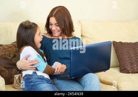 Ouah, c'est génial. Petite fille adorable apprendre à utiliser un ordinateur portable à la maison. Banque D'Images