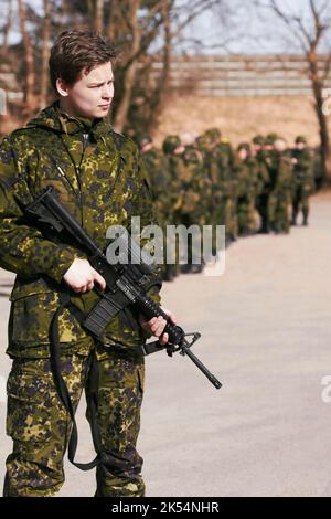 Debout. Un soldat debout avec un fusil et ses compagnons soldats en arrière-plan. Banque D'Images