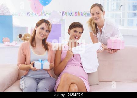 C'est parfait. Une jeune femme enceinte recevant des cadeaux de ses jolies amies à sa douche de bébé. Banque D'Images