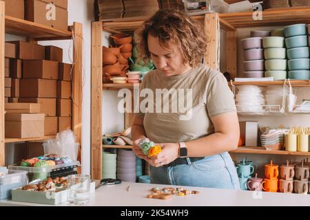 Femme en bois naturel sûr sur le bureau, style écologique. Perles de cerclées. Jouet de dentition avec décoration de ferraillement de cercueil. Travail de fabrication à la main de Banque D'Images