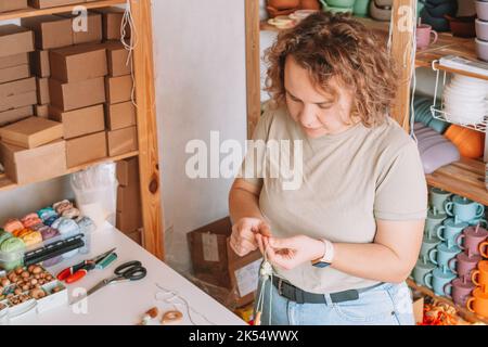 Femme en bois naturel sûr sur le bureau, style écologique. Perles de cerclées. Jouet de dentition avec décoration de ferraillement de cercueil. Travail de fabrication à la main de Banque D'Images