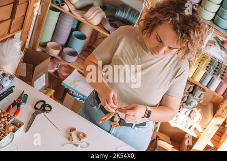 Femme en bois naturel sûr sur le bureau, style écologique. Perles de cerclées. Jouet de dentition avec décoration de ferraillement de cercueil. Travail de fabrication à la main de Banque D'Images