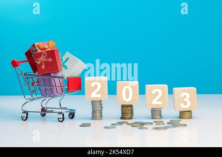 Affaires: cubes en bois sur quatre piles de pièces de monnaie et panier avec boîtes cadeaux en studio sur fond bleu. Business Online concept Banque D'Images