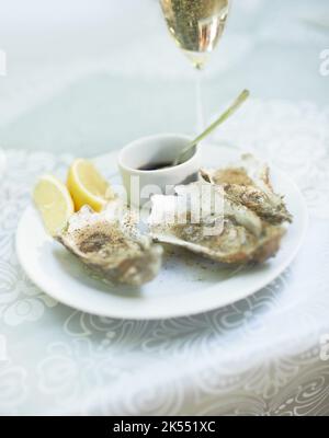 Parfait accompagnement des vins. Une assiette d'huîtres sur une table avec un verre de vin. Banque D'Images