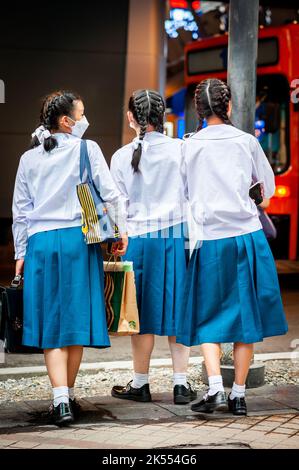 Un groupe de jeunes écolières thaïlandaises attendent le bus à la fin de la journée près de leur école à Sala Daeng, Bangkok, Thaïlande. Banque D'Images