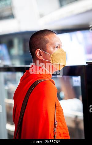 Un moine thaïlandais portant un masque covid attend le train aérien BTS à Bangkok, en Thaïlande. Banque D'Images