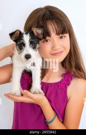 Fille de dix ans portant un chien de chiot Jack Russell Banque D'Images