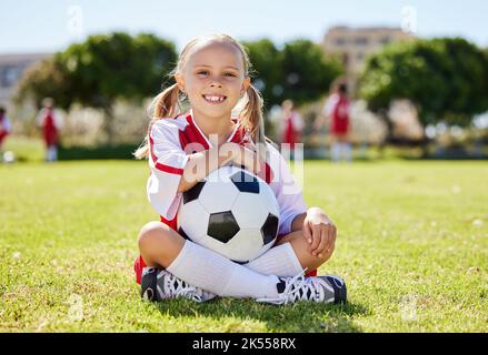 Ballon de football, jeune fille sportive et assis sur le terrain, entraînement pour les jeunes compétition match jouant à l'herbe du stade. Portrait, jeune athlète ou joueur aiment Banque D'Images