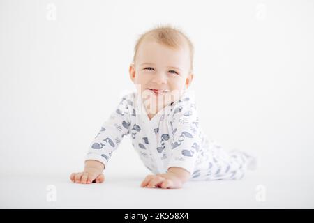 Portrait de bébé garçon souriant et couché en barboteuse sur fond blanc. Banque D'Images