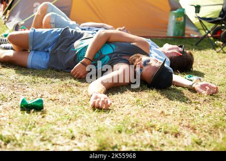 Trop de bières... deux gars sont passés sur l'herbe après avoir bu trop lors d'un festival en plein air. Banque D'Images