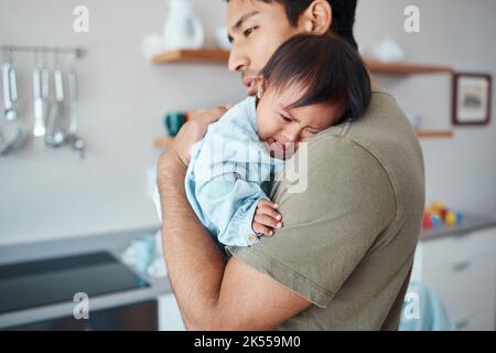 Pleurs, le syndrome de Down bébé et le père tenant, réconfortant et consolant enfant bouleversé dans leur maison avec un parent qui s'occupe. Homme ou papa asiatique montrant l'amour Banque D'Images