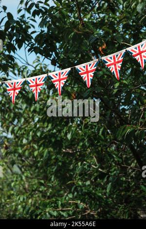 Drapeaux triangulaires de l'Union Jack suspendus dans une avenue bordée d'arbres pour les célébrations du Jubilé de platine de la Reine du Royaume-Uni. Banque D'Images