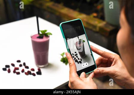 Une femme prenant la photo de smoothie mûrier pour la publicité Banque D'Images