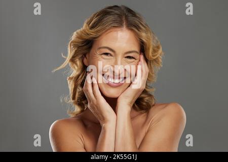 Portrait d'un sourire heureux, beauté et soin de la peau femme mûre regardant positif et gai tout en prenant soin de sa peau. Visage, soins de la peau et cosmétiques Banque D'Images