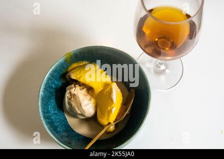 Crème glacée au café et sorbet à la mangue dans un bol vert et un snifter de brandy Banque D'Images